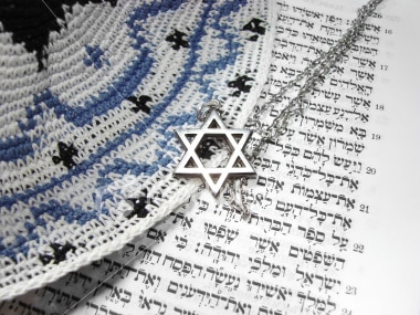 An image of a necklace with the Star of David over top Hebrew letters and a kippah. 