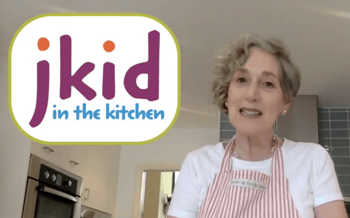 jkid in the kitchen: an image of a woman wearing an apron and smiling, ready to help you make all kinds of delicious foods for shavuot.