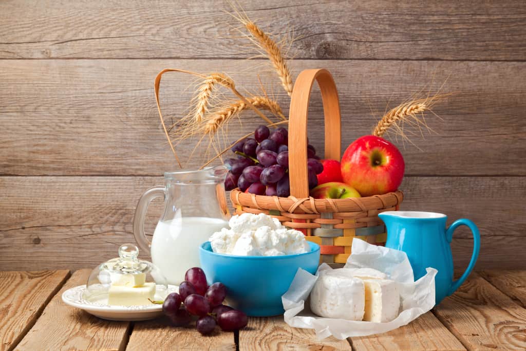 An array of fruits, cheeses, and milk set up in a picnic style to celebrate Shavuot.