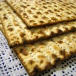 A photograph of three matzah sheets stacked on top of a white lace tablecloth.