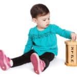 A photograph of a toddler putting a coin into a tzedakah box.