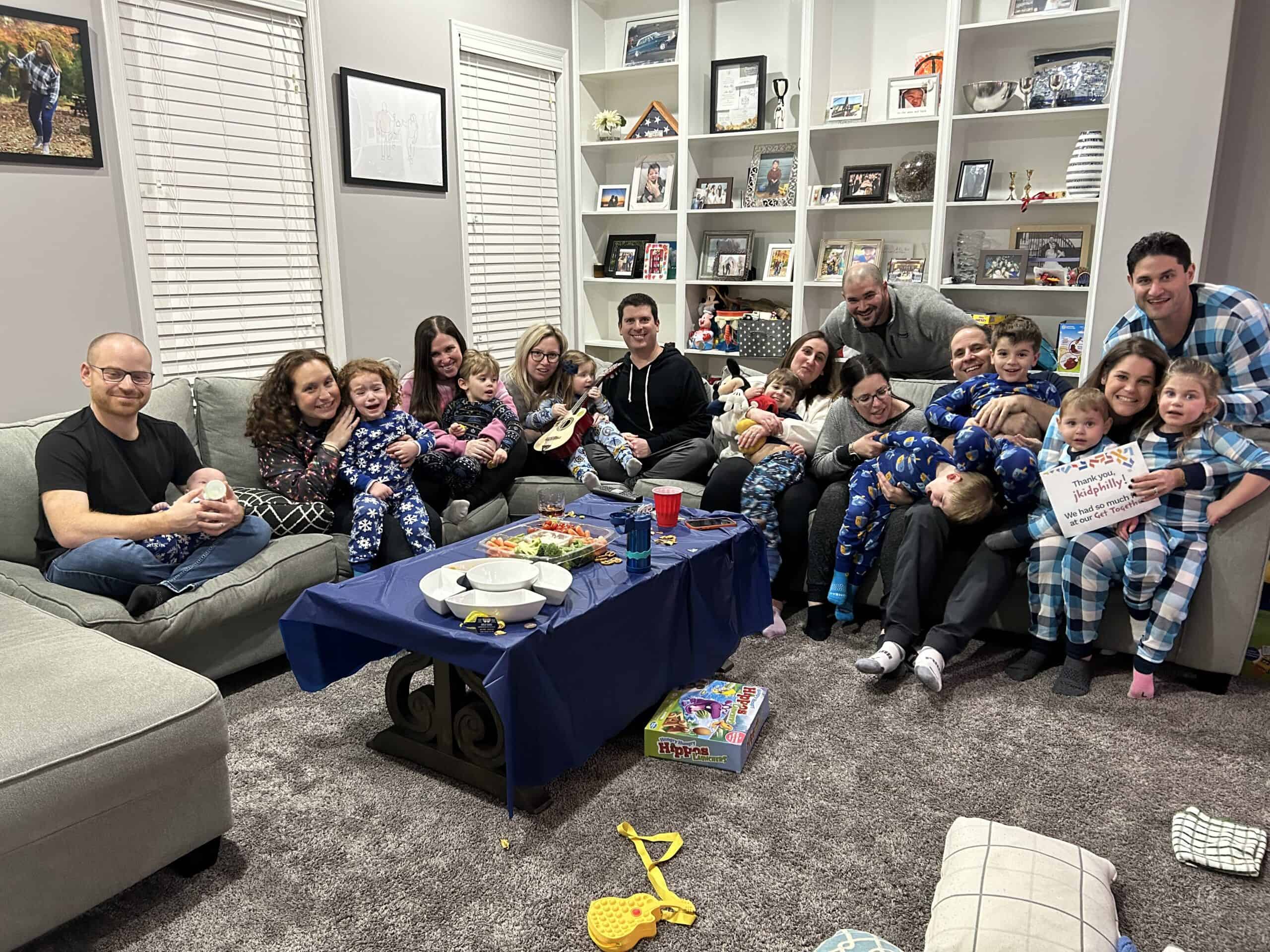 A photo of a large amount of adults, several with children on their laps, sitting on a very long sofa.