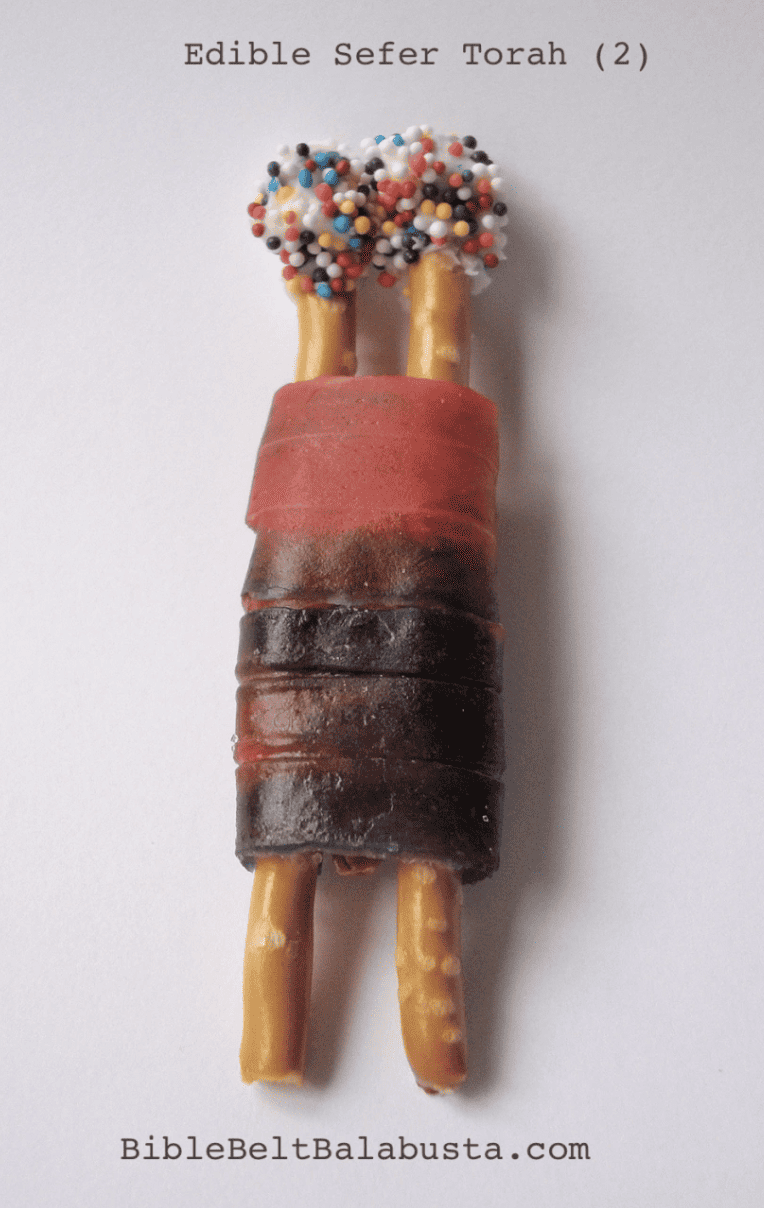 A photo of a mini Torah scroll made out of wrapping pretzel rods in a fruit roll-up.