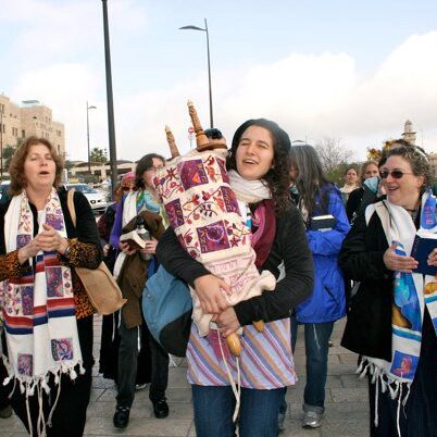 A photo of a bunch of people holding Torah scrolls.