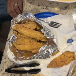 A photo of a bunch of fried fish in aluminum foil