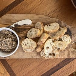 A photo of sliced bread on a cutting board with a cup of mock chopped liver.