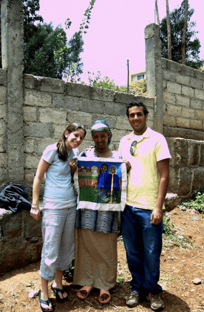 A photo of Erin standing next to two other people, presumably Ethiopian Jews, who are holding an ornate decorated cloth. 